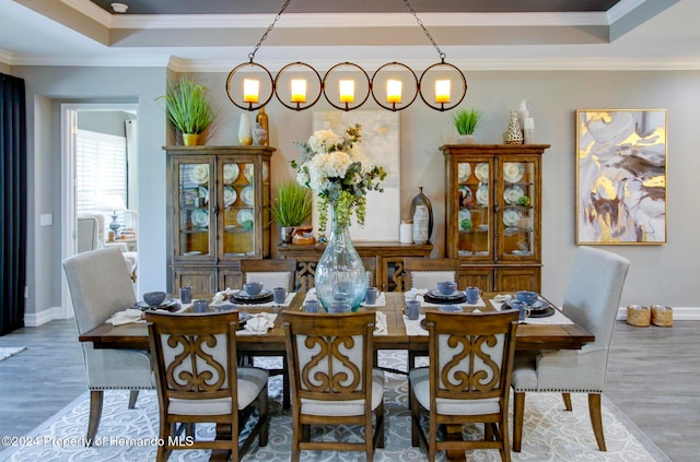 dining area featuring wood-type flooring, crown molding, and a tray ceiling