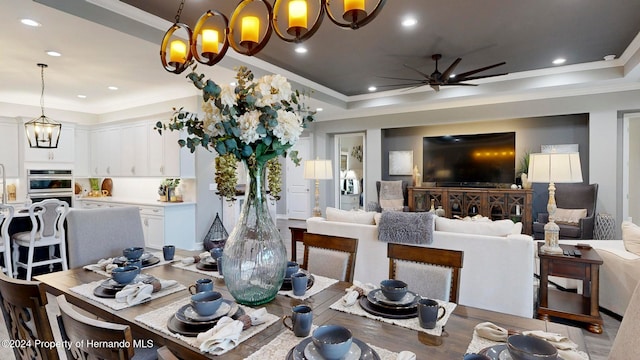 dining space featuring ornamental molding, wood-type flooring, and a raised ceiling