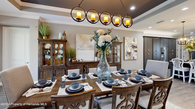 dining space featuring a raised ceiling, light hardwood / wood-style floors, and crown molding