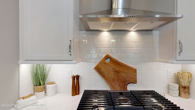 room details featuring white cabinetry, decorative backsplash, and wall chimney exhaust hood