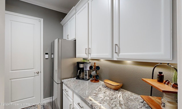 kitchen featuring hardwood / wood-style flooring, white cabinetry, light stone countertops, crown molding, and stainless steel fridge