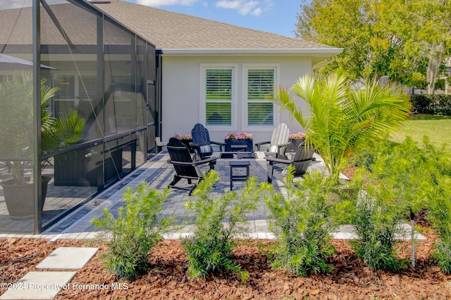 view of patio featuring a lanai and an outdoor living space with a fire pit