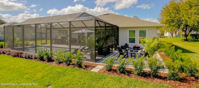 back of house featuring glass enclosure, a patio area, and a yard