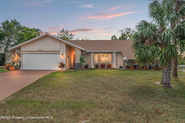 single story home featuring a garage and a yard