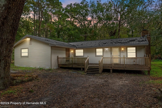 back house at dusk with a wooden deck