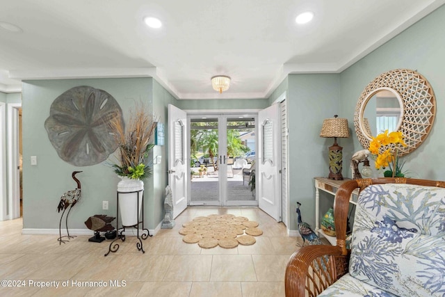 tiled foyer with crown molding and french doors