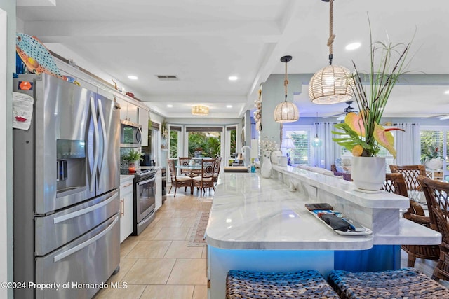 kitchen featuring kitchen peninsula, a wealth of natural light, pendant lighting, and appliances with stainless steel finishes