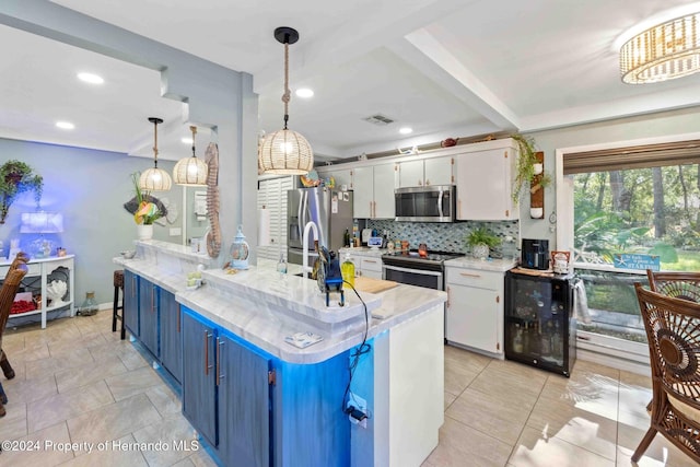 kitchen with tasteful backsplash, stainless steel appliances, white cabinetry, blue cabinetry, and pendant lighting