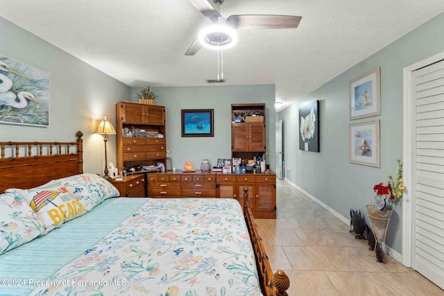 bedroom with ceiling fan, a textured ceiling, and light tile patterned floors