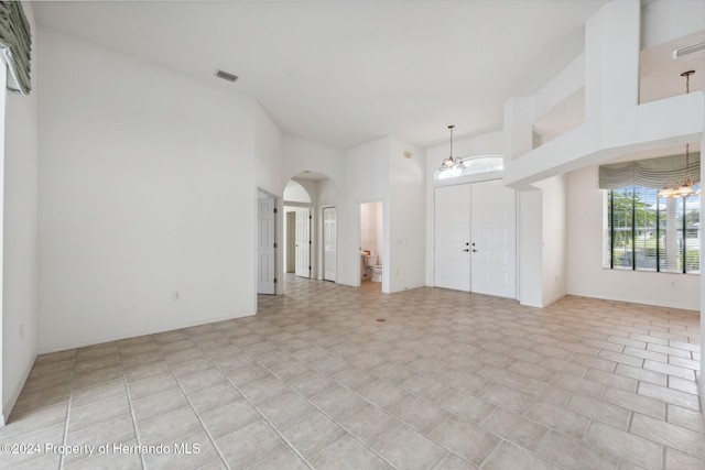 empty room featuring a towering ceiling and a chandelier