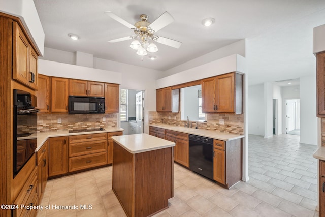 kitchen with a center island, backsplash, black appliances, sink, and ceiling fan