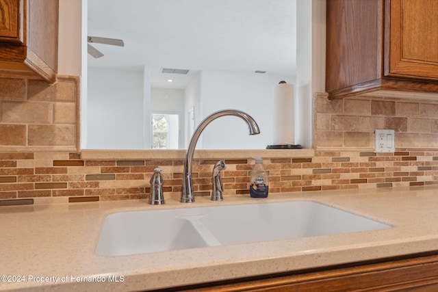 room details with decorative backsplash, light stone countertops, and sink