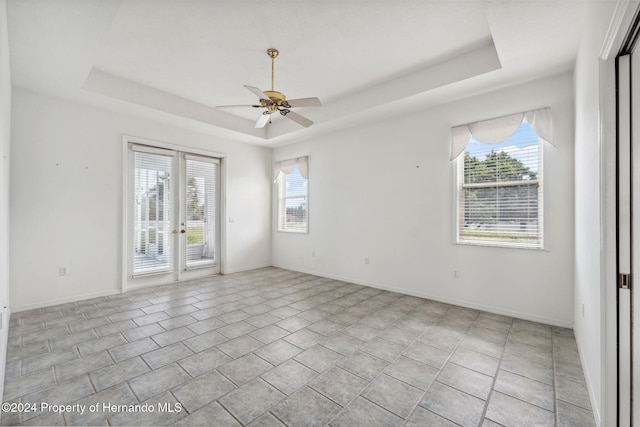 spare room with plenty of natural light, ceiling fan, and a raised ceiling