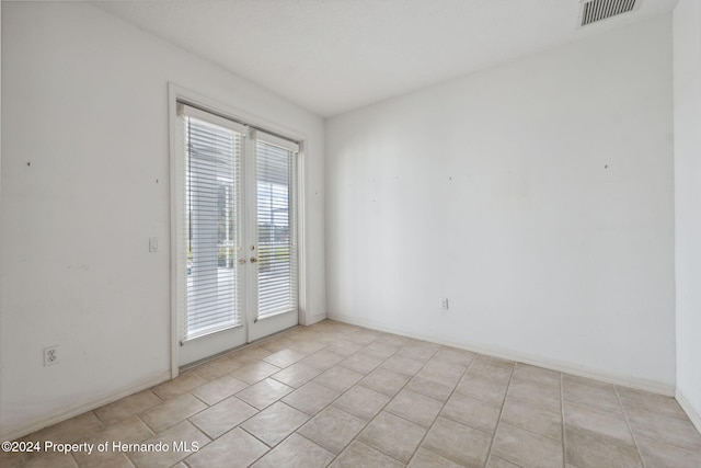 unfurnished room with light tile patterned floors and french doors