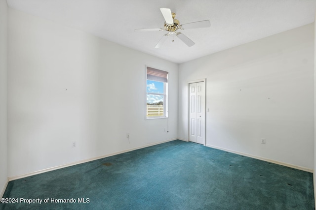 unfurnished room with ceiling fan and dark carpet