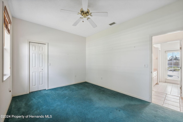 carpeted spare room featuring ceiling fan