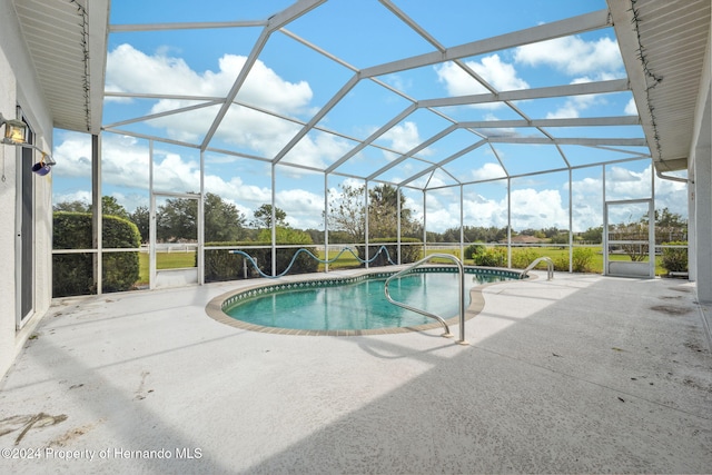 view of swimming pool with glass enclosure and a patio area