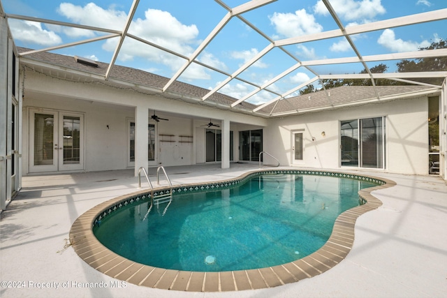 view of swimming pool with ceiling fan, a patio area, and glass enclosure