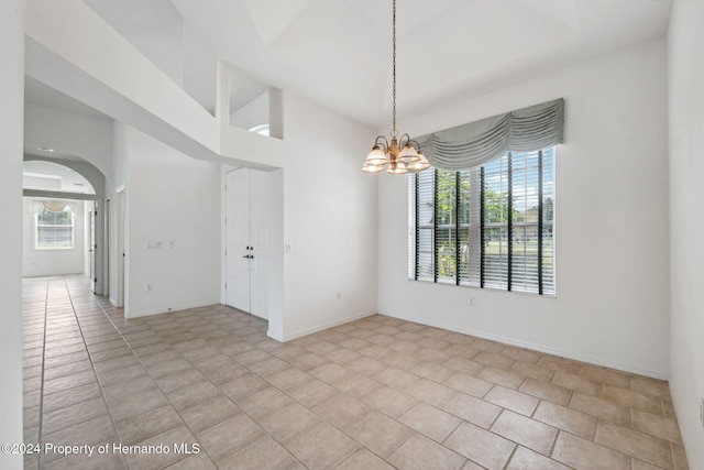 tiled spare room featuring an inviting chandelier