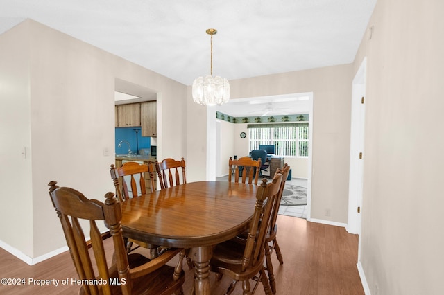 dining room with ceiling fan with notable chandelier and dark wood-type flooring