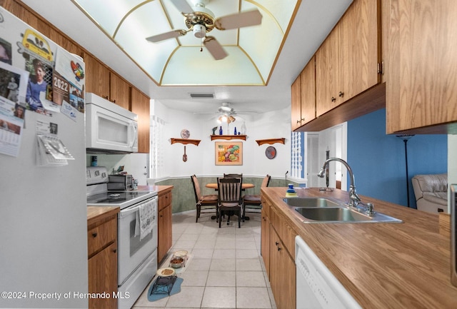 kitchen with light tile patterned flooring, white appliances, and sink