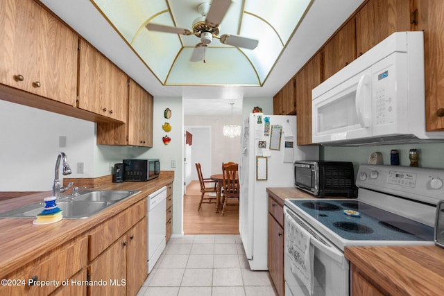 kitchen featuring ceiling fan with notable chandelier, white appliances, sink, and light tile patterned floors