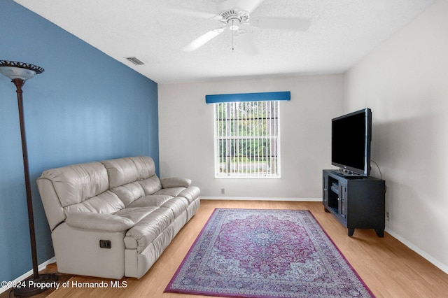 living room with ceiling fan, a textured ceiling, and hardwood / wood-style flooring