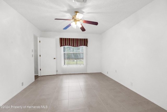 tiled empty room featuring ceiling fan