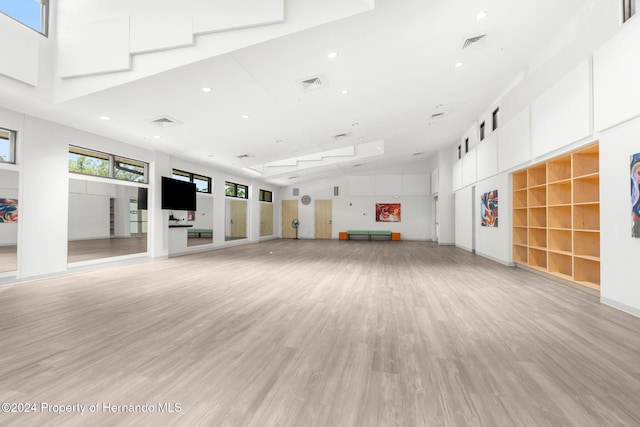 unfurnished living room featuring light hardwood / wood-style floors and a high ceiling