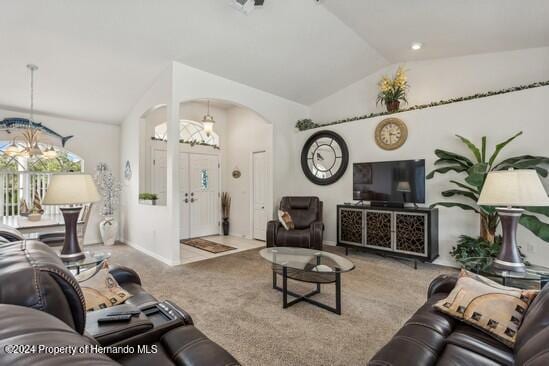 carpeted living room with lofted ceiling and an inviting chandelier