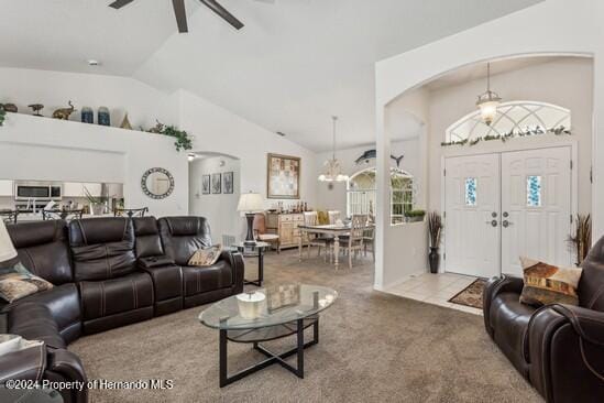 carpeted living room featuring ceiling fan with notable chandelier and high vaulted ceiling