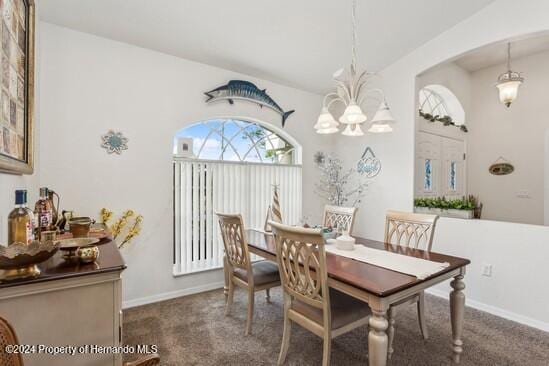 dining area featuring an inviting chandelier and dark colored carpet