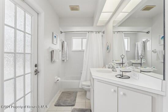 full bathroom featuring tile patterned flooring, vanity, shower / bath combo, and toilet