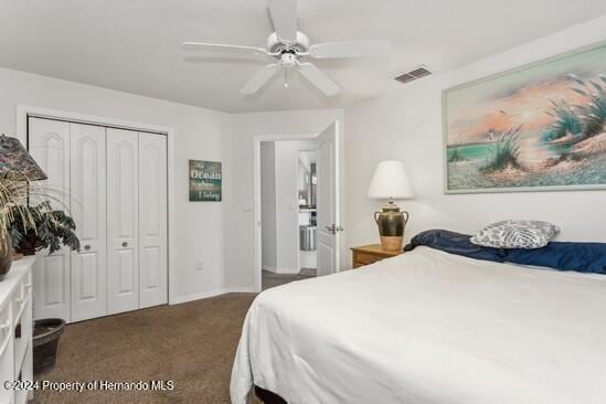 bedroom with ceiling fan, dark carpet, and a closet