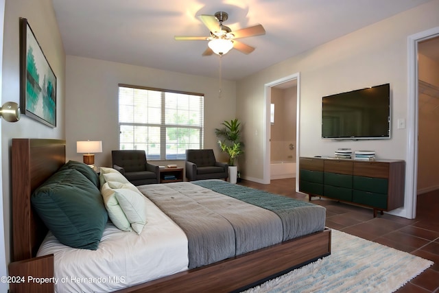 bedroom with connected bathroom, dark tile patterned floors, and ceiling fan