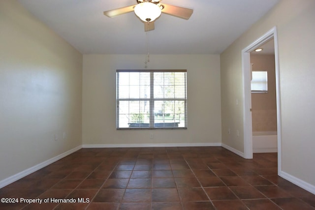 tiled spare room with ceiling fan