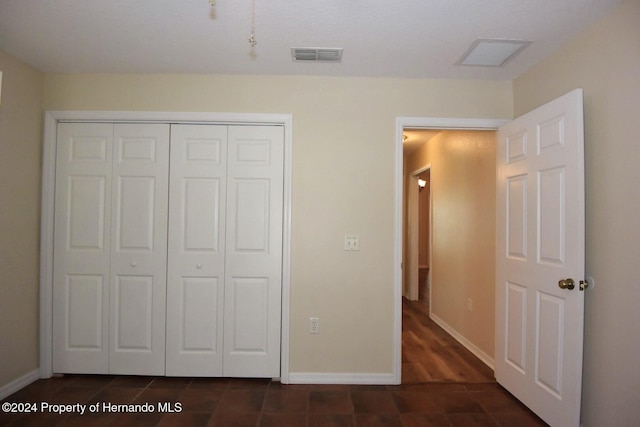 unfurnished bedroom featuring dark wood-type flooring and a closet