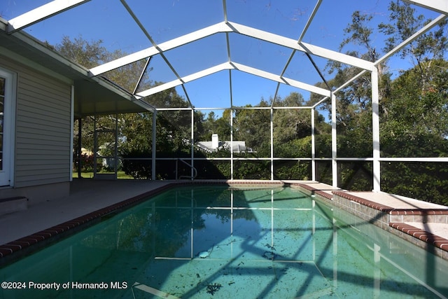 view of swimming pool featuring a lanai and a patio area