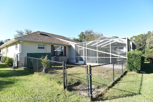 view of property exterior featuring glass enclosure and a lawn