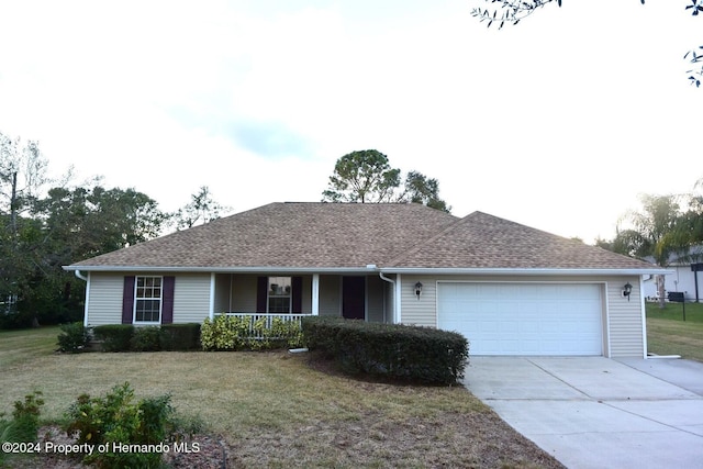 ranch-style house with covered porch, a garage, and a front lawn