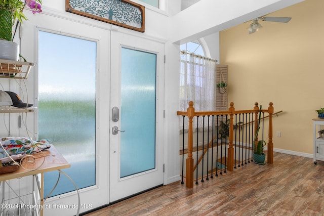 foyer with hardwood / wood-style floors, a towering ceiling, and french doors