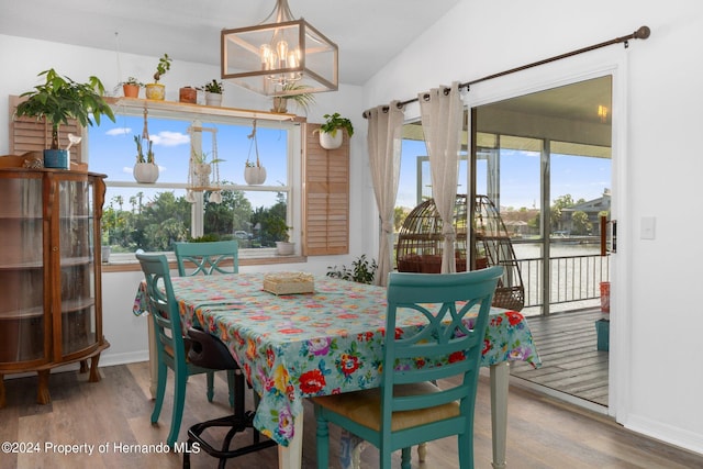 dining space with lofted ceiling, hardwood / wood-style flooring, and a notable chandelier