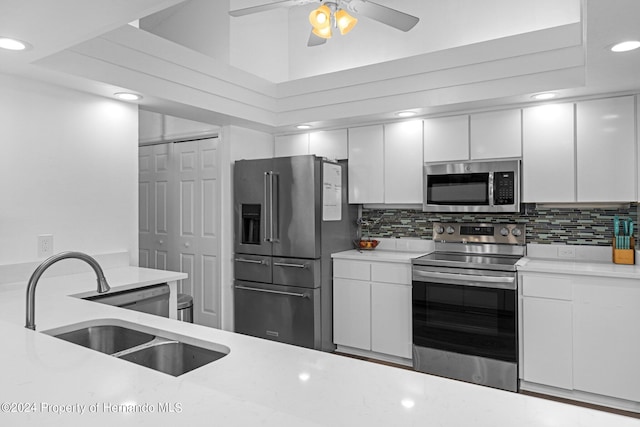 kitchen featuring stainless steel appliances, sink, ceiling fan, white cabinets, and decorative backsplash