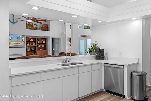 kitchen featuring light hardwood / wood-style floors, white cabinets, kitchen peninsula, sink, and stainless steel dishwasher