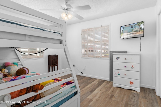 bedroom with ceiling fan, multiple windows, light wood-type flooring, and a textured ceiling