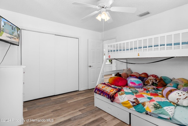 bedroom featuring hardwood / wood-style floors, ceiling fan, a textured ceiling, and a closet