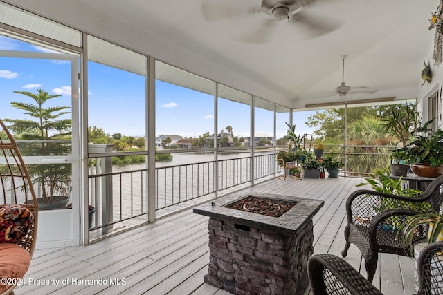 sunroom featuring ceiling fan and a water view