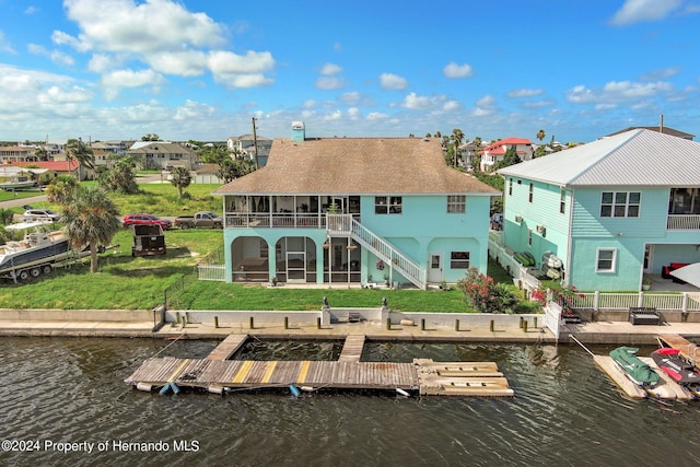 back of property featuring a yard, a deck with water view, a sunroom, and a patio