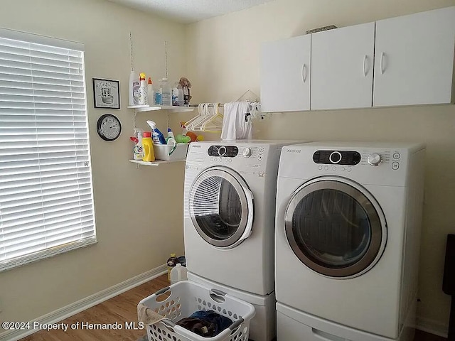 washroom featuring separate washer and dryer, wood-type flooring, and cabinets