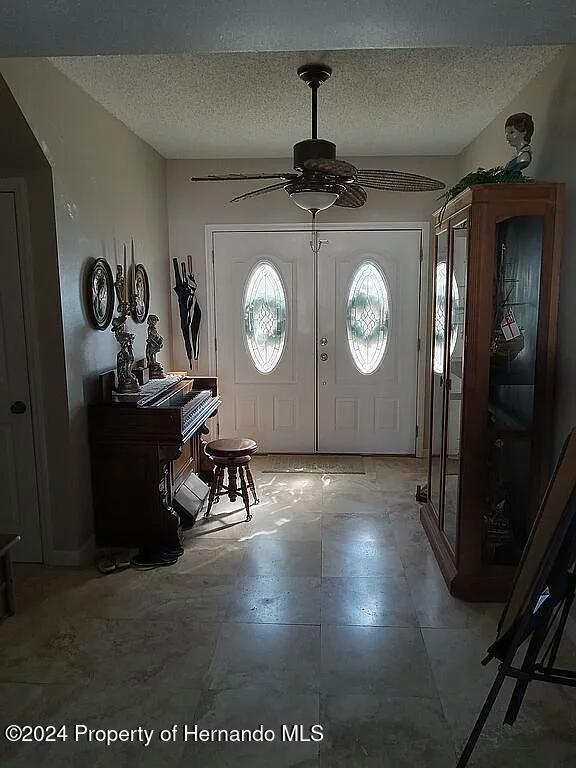 foyer entrance featuring ceiling fan and a textured ceiling